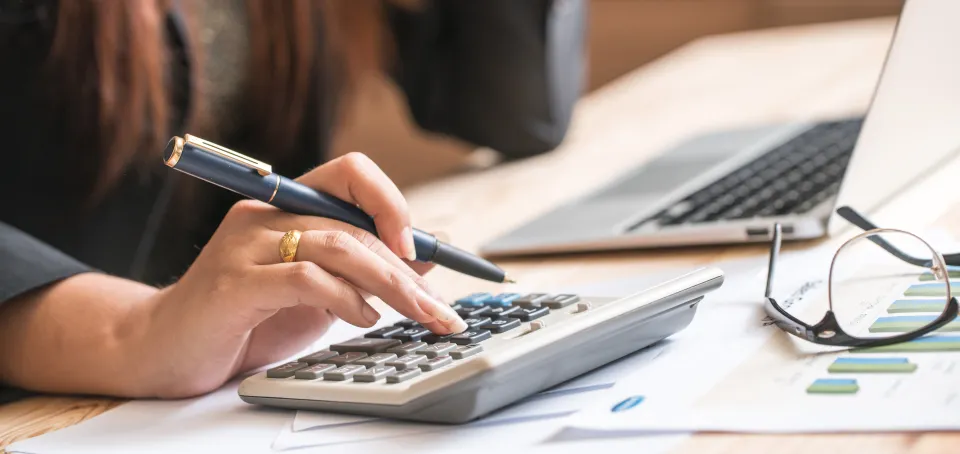 Woman working at a laptop and using a calculator