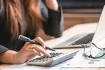 Woman working at a laptop and using a calculator