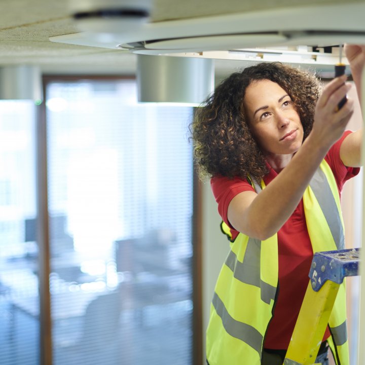 Female tradesperson adjusting lighting in ceiling