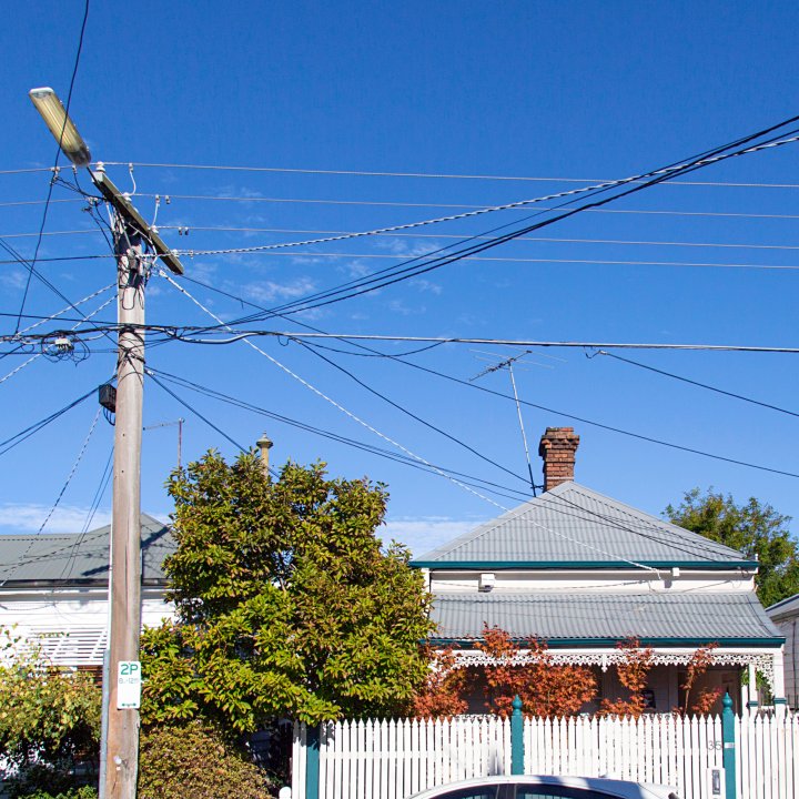 Outside street view of electrical power lines and suburban rooftops skyline Close