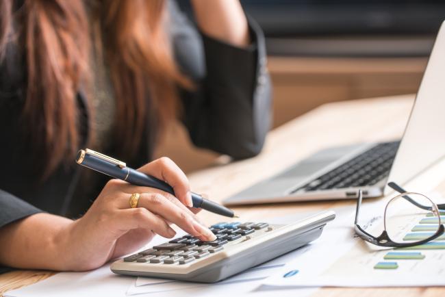 Woman working at a laptop and using a calculator