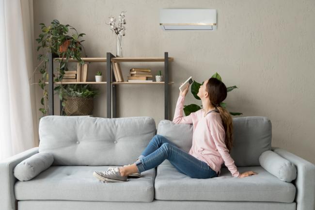 Woman sitting on couch underneath an air conditioner
