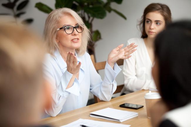 Woman speaking to colleagues around a table
