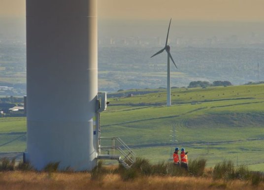 Workers standing beside a wind turbine