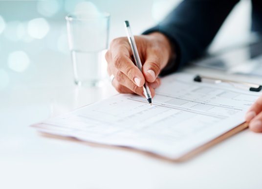 Mans hand with pen and clipboard